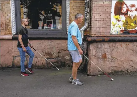  ?? Jae C. Hong Associated Press ?? IVAN Soroka, left, and Oleksandr Zhylchenko, two Ukrainian soldiers blinded in the war, use their canes to navigate the streets of Rivne.