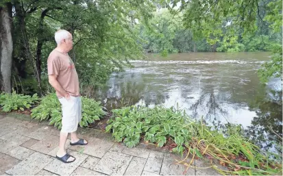  ?? MIKE DE SISTI / MILWAUKEE JOURNAL SENTINEL ?? Fiddlehead­s Coffee co-owner Ray Marcy monitors the rising Milwaukee River behind the business on North Cedarburg Road in Thiensvill­e on Wednesday.