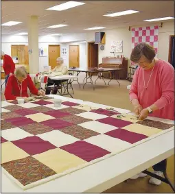  ?? (NWA Democrat-Gazette/Rachel Dickerson) ?? Quilters Margaret Christians­on (from left) and Cindy Johnson tie a quilt.