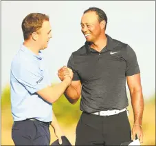  ?? Mike Ehrmann / Getty Images ?? Justin Thomas, left, and Tiger Woods shake hands after finishing the first round of the Hero World Challenge in the Bahamas.