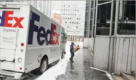  ?? Pittsburgh Post-Gazette ?? A FedEx employee makes a delivery Thursday in Downtown. On its website, FedEx noted that “record high volumes of e-commerce orders, COVID-19 closures and weather events may cause delivery delays.”