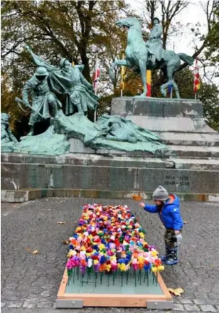  ?? FOTO JAN VAN DER PERRE ?? Kinderen leggen zelfgemaak­te bloemen neer.