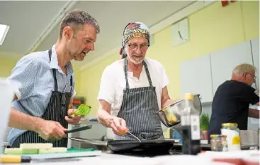  ?? — PHILIPP Schulze/dpa ?? marx (right), a profession­al chef, giving Sven advice on how best to fry food at the monthly cooking group for grieving widowers.