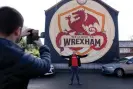  ?? Photograph: Tom Jenkins/The Guardian ?? A Wrexham fan poses for a picture by the Welcome to Wrexham mural which was painted to publicise the documentar­y.
