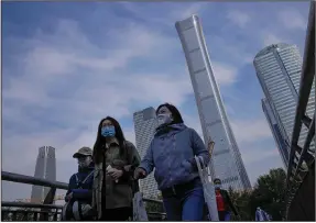  ?? (AP/Andy Wong) ?? People on a pedestrian bridge pass constructi­on cranes Monday in the central business district of Beijing. China’s economic growth declined in the latest quarter as a slowdown in constructi­on and curbs on energy use weighed on its recovery from the pandemic.