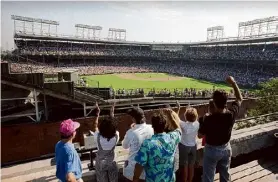  ?? Seth Perlman/Associated Press ?? Spectators watch an All-Star Game practice session from the roof of a building just outside Chicago’s Wrigley Field. Booking hotels for baseball games during shoulder seasons like May, June or September can often be cheaper than the summer months. Additional­ly, save money by planning to attend weekday versus weekend games.