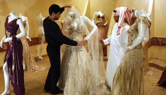  ?? THE ASSOCIATED PRESS ?? A Saudi man buys a wedding dress at a shop in Riyadh, Saudi Arabia. Many nations, including Saudi Arabia, give financial assistance to grooms.
