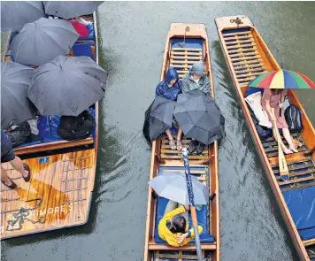  ??  ?? People getting a soaking while out punting on the Cam in Cambridge yesterday morning as the inclement weather continues