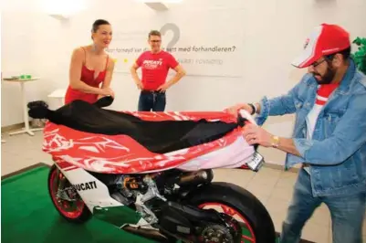  ?? FOTO: TOR MJAALAND ?? Tariq Mahmood (t.h.) avduker sin nye Ducati til godt over en halv million kroner. Godt assistert av nabo og for anledninge­n «paraplydam­e» Elin Bemicas. Geir Helle fra Ducati-klubben følger spent med.