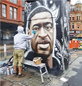  ?? Picture: Reuters ?? THE FACE OF PROTEST. Artist Akse works on a mural of George Floyd in Stevenson Square, Manchester, Britain.