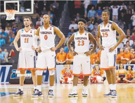  ?? Gerry Broome, The Associated Press ?? Virginia’s Ty Jerome, Devon Hall, Nigel Johnson and Mamadi Diakite, from left, watch as a UMBC player shoots free throws during the second half of the top-seeded Cavaliers’ first-round loss Friday night in the NCAA Tournament.