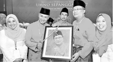  ??  ?? Yakub (left) presenting Rahman with a souvenir for officiatin­g at the Umno Sepanggar delegates meeting.