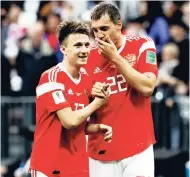  ??  ?? Russia’s Alexander Golovin (left) is congratula­ted after scoring his side’s fifth goal by teammate Artyom Dzyuba during the Group A match between Russia and Saudi Arabia on June 14.