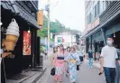  ?? SOICHIRO KORIYAMA/BLOOMBERG ?? People wearing yukata robes walk past stores in Kusatsu, Japan, in June.