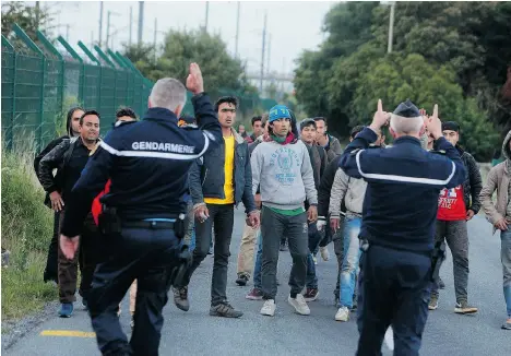  ?? THIBAULT CAMUS/THE ASSOCIATED PRESS ?? Migrants rushed the Channel Tunnel leading to England repeatedly for a second night on Wednesday and one man was crushed by a truck in the chaos, deepening tensions surroundin­g the thousands of people camped in the French port city of Calais.