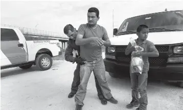  ?? CAROLYN COLE/LOS ANGELES TIMES ?? David Martinez, 31, and his 11-year-old son are detained by Border Patrol Agent Robert Rodriguez. The new “zero tolerance” immigratio­n policy implemente­d by the Trump administra­tion has led to packed federal courtrooms, especially in southern Texas.