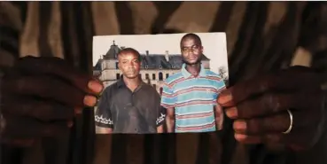  ??  ?? Samba Issa Anne holding a photograph of his son Amadou Anne, right, with a friend. Amadou Anne died trying to reach Europe