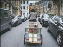  ??  ?? Belgian artist Elke Lemmens rides with her custom-made trailer on her way to making miniature installati­ons in boot-scrapers in Antwerp, Belgium. (AP/Virginia Mayo)