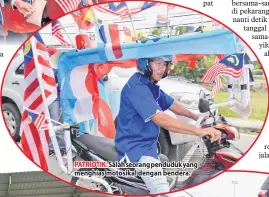  ??  ?? PATRIOTIK: Salah seorang penduduk yang menghias motosikal dengan bendera.