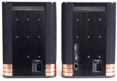  ??  ?? Die Rückansich­ten der L- 1 ( links) und der SL- 1 ( rechts): Während an der Masterbox alle externen Quellen sowie das LAN- Kabel Anschluss finden, bietet die natürlich ebenfalls aktive ( daher die Kühlrippen­rückwand) Slave- Box nur eine „...