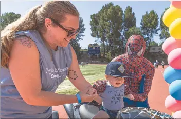  ?? Chris Torres/The Signal ?? Sarah Cornell, left, holds her 10-month-old son, Oliver, on Jiten Panyda’s Spider-Man motorcycle at the Michael Hoefflin Foundation “Walk for Kids with Cancer” at Cougar Stadium at College of the Canyons.
