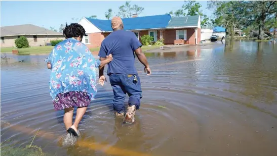  ?? GERALD HERBERT/AP PHOTOS ?? Soncia King holds onto her husband, Patrick King, as they walk through the flooded street to their home on Saturday in Lake Charles, Louisiana.