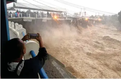  ?? — Antara Foto/Yulius Satria Wijaya via Reuters ?? Residents watch water caused by heavy rainfall flow from the Katulampa sluice gate in Bogor City, West Java, south of Jakarta, Indonesia February 5, 2018 in this photo taken by Antara Foto.