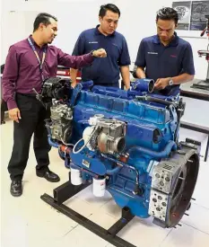  ??  ?? Mechanics studying a diesel bus engine under the guidance of their instructor (left).