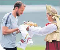  ??  ?? Gareth Southgate accepts a gift of karavai – a type of Russia bread – at the team’s HQ