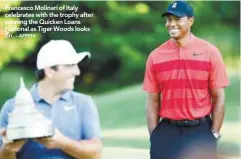  ?? – AFPPIX ?? Francesco Molinari of Italy celebrates with the trophy after winning the Quicken Loans National as Tiger Woods looks on.