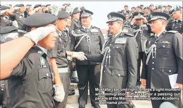  ??  ?? Mustafar (second right) shares a light moment with Immigratio­n officers after a passing out parade at the Malaysian Immigratio­n Academy. — Bernama photo