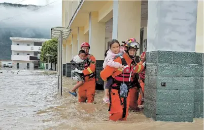  ??  ?? Firefighte­rs evacuate children from flooded areas in Mianning County in Sichuan Province on Saturday. Torrential downpours have left three people dead in the province. — CNS