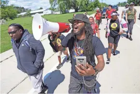  ?? MIKE DE SISTI / MILWAUKEE JOURNAL SENTINEL ?? Protest leader Frank Sensabaugh, right, who goes by Frank Nitty, starts his march to Washington, D.C., along Highway 31 in Caledonia with community activist Tory Lowe, far left, on Aug. 4.