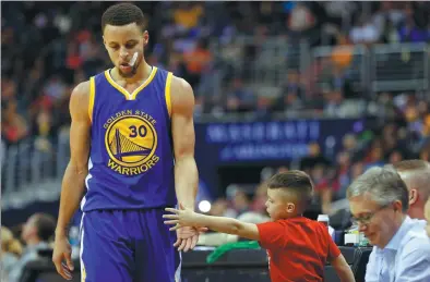  ?? GEOFF BURKE / USA TODAY SPORTS ?? Golden State Warriors guard Stephen Curry shakes hands with a young fan while exiting Wednesday’s game against the Washington Wizards at Verizon Center in Washington. The Warriors won 134- 121.