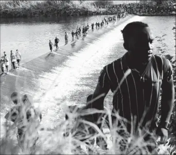  ?? REUTERS/Go Nakamura ?? Migrants seeking asylum in the U.S. walk in the Rio Grande river near the Internatio­nal Bridge between Mexico and the U.S., as they wait to be processed, in Ciudad Acuna, Mexico, September 16, 2021. According to officials, some migrants cross back and forth into Mexico to buy food and supplies.