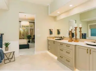  ??  ?? Semi-polished ceramic tile clads master ensuite surfaces where modified Shaker-style, maple cabinets in Ash Grey host LED under-cabinet lighting. Dual vessel sinks with black bases contrast with white quartz countertop­s against a backsplash of hexagon ceramic tile.