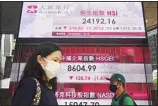  ?? ?? People wearing face masks walk past a bank’s electronic board showing the Hong Kong share index at Hong Kong Stock Exchange in Hong Kong Monday, Sept. 27, 2021. Asian share rose Monday. (AP)