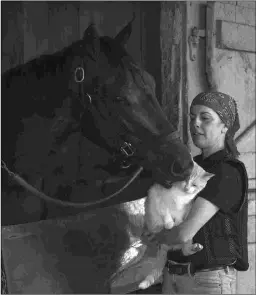  ?? BARBARA D. LIVINGSTON ?? Morticia, a three-time stakes winner, gets a feline visitor Friday held by Sarah Arnold, the wife of trainer Rusty.