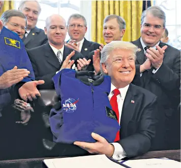  ??  ?? Donald Trump receives a Nasa jacket as he signs the spending bill for the space agency at the Oval Office yesterday