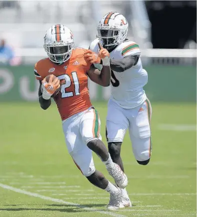  ?? MICHAEL LAUGHLIN / SOUTH FLORIDA SUN SENTINEL ?? Miami running back Henry Parrish Jr. gets pushed out of bounds by James Williams during the Hurricanes’ spring game Saturday at DRV PNK Stadium.