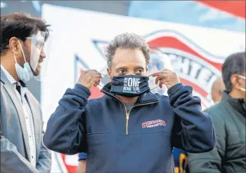  ?? ARMANDO L. SANCHEZ/CHICAGO TRIBUNE ?? Mayor Lori Lightfoot puts her mask on after speaking during a post-election drive-up celebratio­n at the 87th Street shopping center in theWest Chatham neighborho­od Nov. 8 in Chicago.