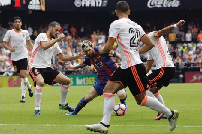  ??  ?? VALENCIA: FC Barcelona’s Lionel Messi, center, duels for the ball during the Spanish La Liga soccer match between Valencia and FC Barcelona at the Mestalla stadium in Valencia, Spain, yesterday.