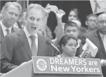  ?? ASSOCIATED PRESS ?? New York Attorney General Eric Schneiderm­an, at podium, speaks at a news conference in New York, surrounded by beneficiar­ies of the Deferred Action for Childhood Arrivals program and their supporters.