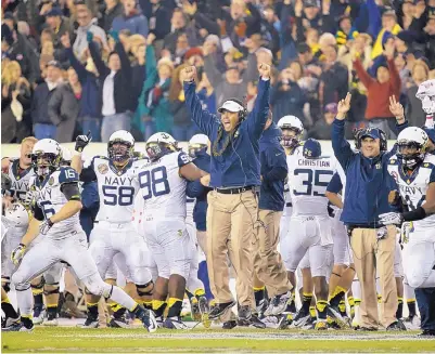  ?? AP FILE ?? Navy head coach Ken Niumatalol­o, center, celebrates during the Midshipmen’s win over Army in 2012. Niumatalol­o is the first coach in the Army-Navy rivalry to win his first eight games.