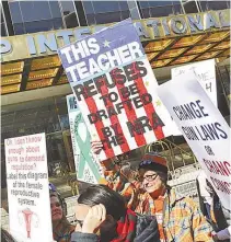  ?? FOTOS AFP ?? Pessoas com cartazes andam na frente do Trump Hotel, em Nova York