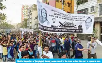  ?? —AFP ?? DHAKA: Supporters of Bangladesh Awami League march in the street as they take part in a general election campaign procession in Dhaka.