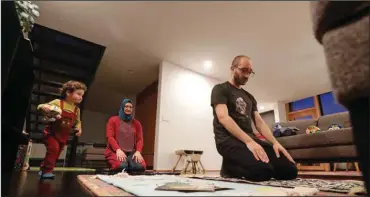  ?? (AP/Elaine Thompson) ?? Ahmad Kamel (right) performs the Maghrib prayer with his wife, Nadia Chaouch, as their son Ahmad Kamel runs past after the family broke the Ramadan daily fast just after sunset in their home last April during the coronaviru­s outbreak in Seattle.