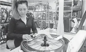  ??  ?? April Xayasith applies decals to finished wheels at HED Cycling, a family-owned business that makes high-end cycling components. JASPER COLT/USA TODAY