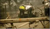  ?? THE ASSOCIATED PRESS ?? A downed power utility pole lies across a road as Eric England, right, searches through a friend’s vehicle after the Camp Fire burned through Paradise in November 2018.