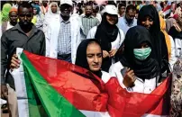  ?? AP ?? A protester carries a Sudanese flag as they chant slogans against military rule and demand the prosecutio­n of former officials at the Armed Forces Square in Khartoum. —